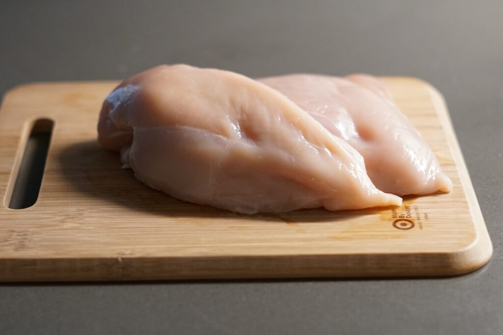 a piece of raw chicken on a cutting board